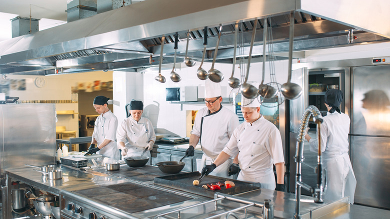 A group of chefs in uniforms working together in an industrial kitchen