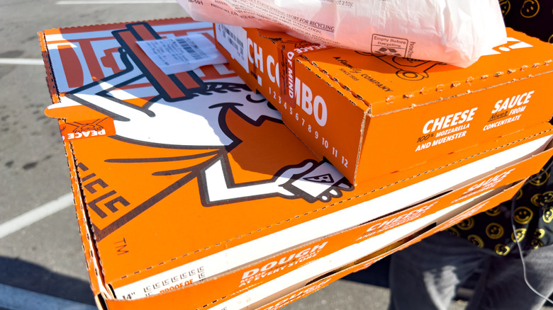Person holding stack of Little Caesars pizza and bread.