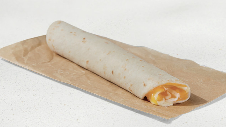Taco Bell cheesy roll up on paper on countertop.