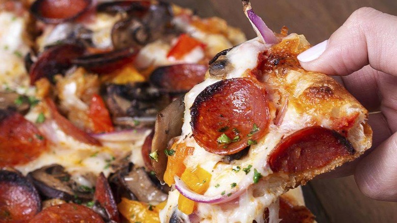 Hand holding slice of Everything Flatbread Pizza