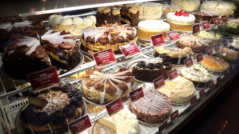 Array of Cheesecake Factory's cheesecakes in display case.