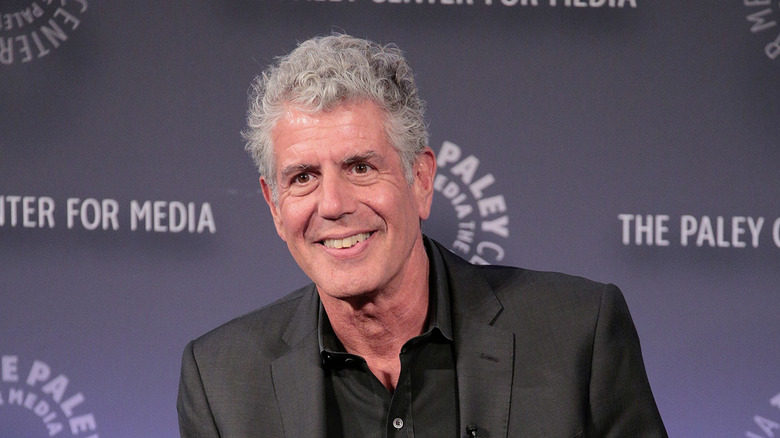 Anthony Bourdain smiling while sitting at a public event