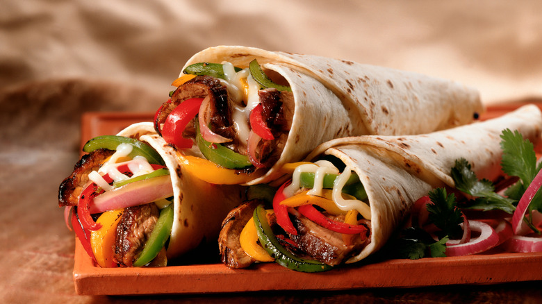 Rolled up Tex Mex burritos sit on a plate