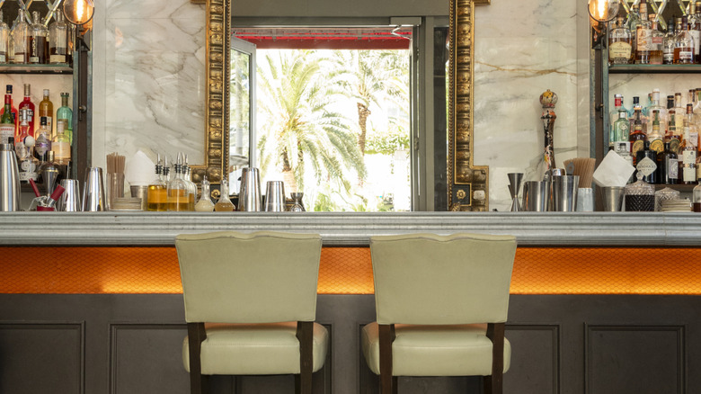 LPM Miami bar on a sunny day with two stools and a window with palm trees outside