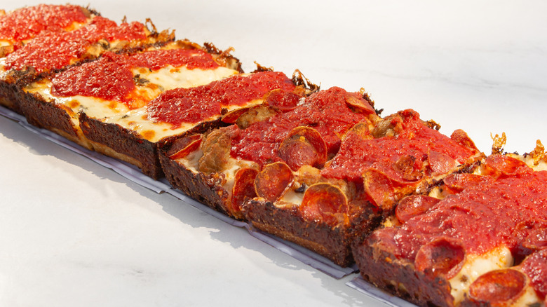 Line of Detroit-style pizzas with caramelized cheese crusts.