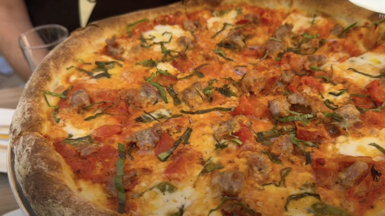 Close-up of a thick crust pizza with cheese, basil, and meat