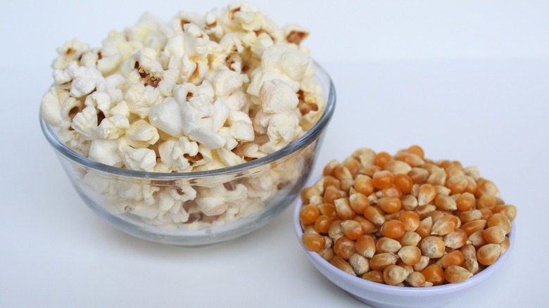 Popcorn in bowl next to popcorn kernels