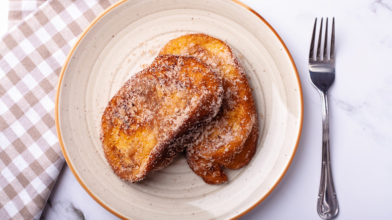 Plate with 2 pieces of french toast next to fork