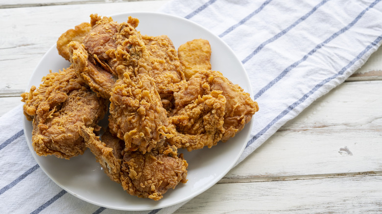A plate of crispy fried chicken on a white table