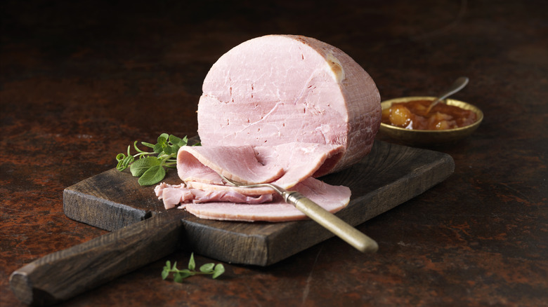Light pink, sliced ham on wood board