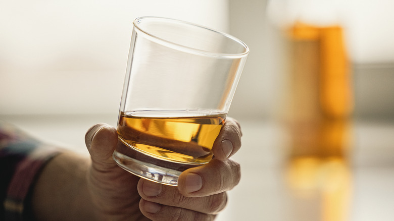 A person holding a glass of whiskey.