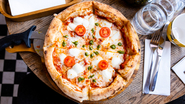 A sliced margherita pizza on a table in a restaurant