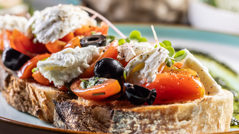 Caprese salad with tomatoes, olives, and mozzarella on a crostini
