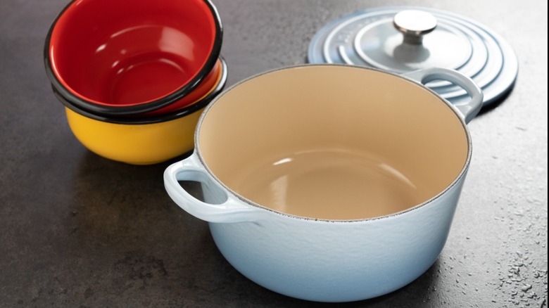 slate blue dutch oven with lid off near ceramic dishes