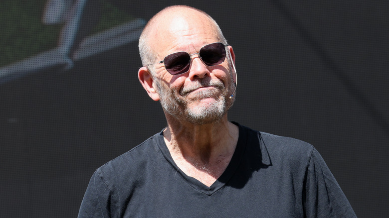 Alton Brown outside with sunglasses and a microphone on.