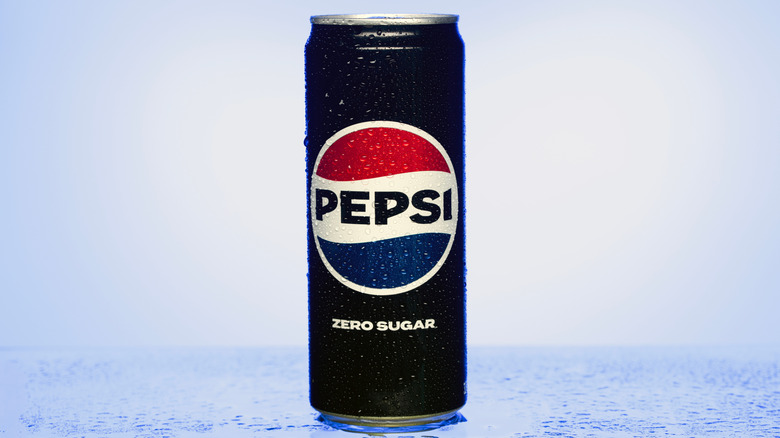 A can of Pepsi Zero Sugar with condensation on it standing on a wet blue countertop