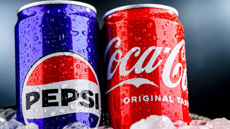 A can of Pepsi aside a can of Coca-Cola, standing in ice