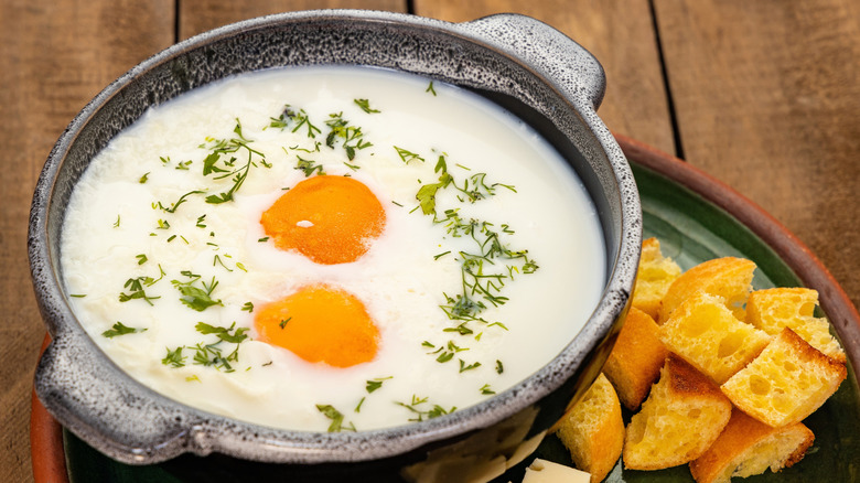 Bowl of changua with bread pieces and blocks of cheese