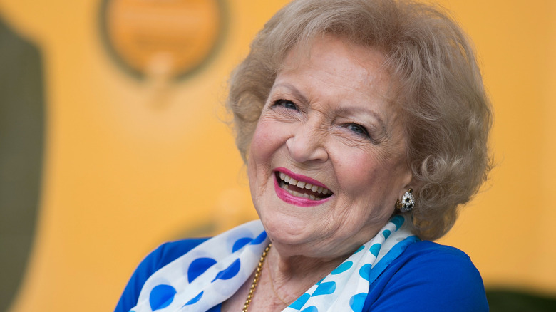 Betty White smiling in blue blouse and polka dot scarf