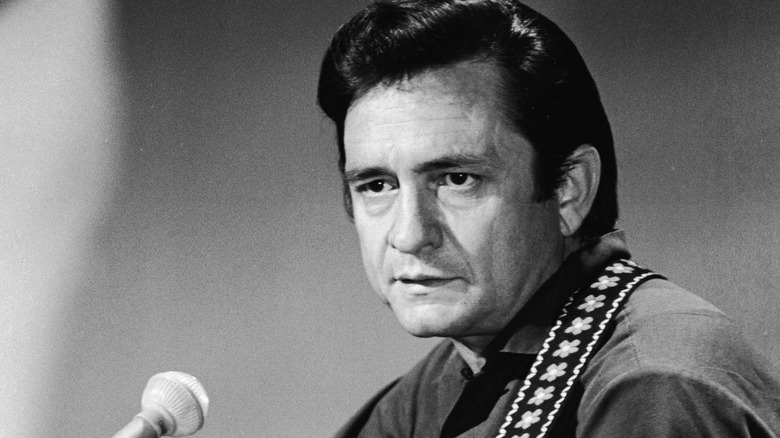 black and white photo of Johnny Cash in front of microphone