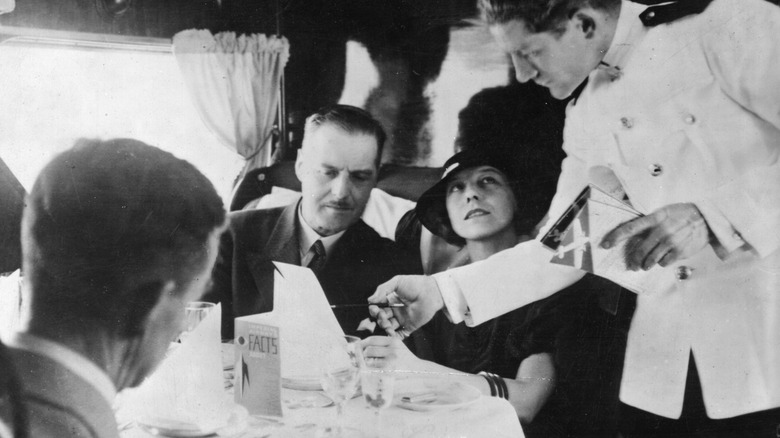 Passengers aboard a Qantas airliner are served by a waiter in 1934
