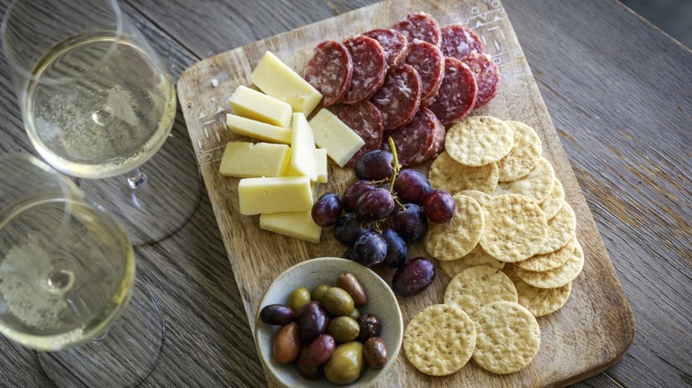 A charcuterie board with meats, cheeses, and olives.