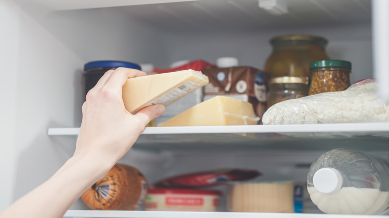 person removing cheese from a refrigerator
