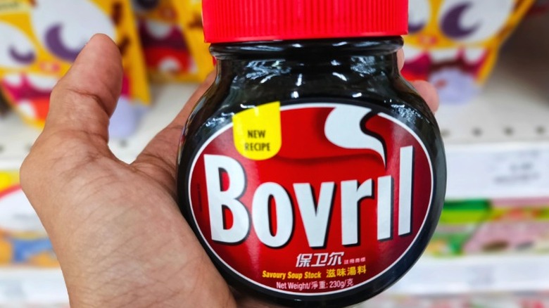 A hand holding a jar of Bovril.