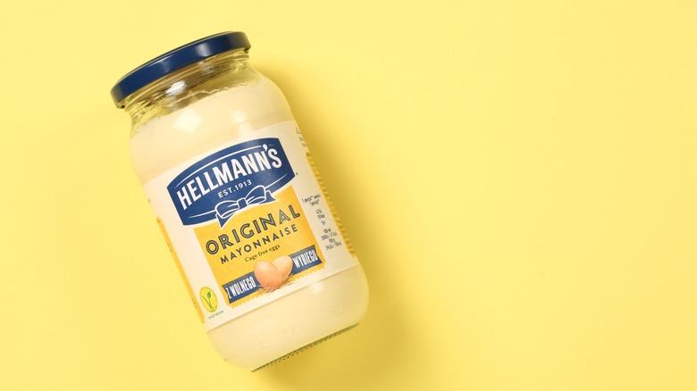 A jar of Hellmann's mayonnaise on a yellow background.