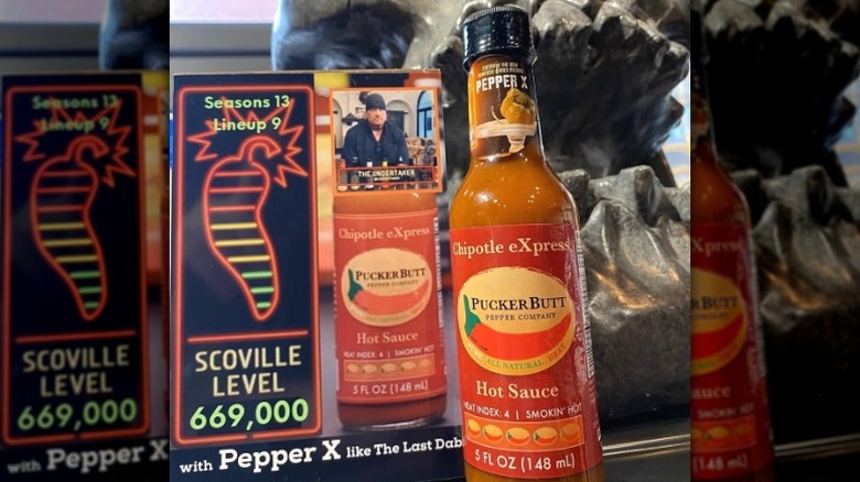 A bottle of Puckerbutt Pepper Company Chipotle Express Hot Sauce with associated Hot Ones memerobilia.