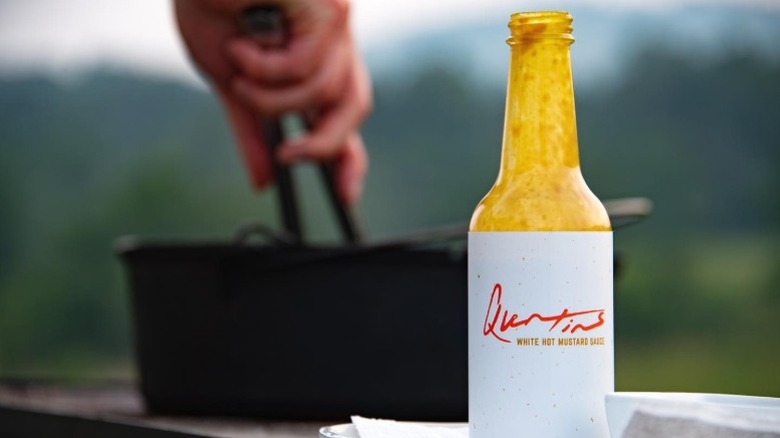 A bottle of Quentin's White Hot Mustard Sauce before a grill.