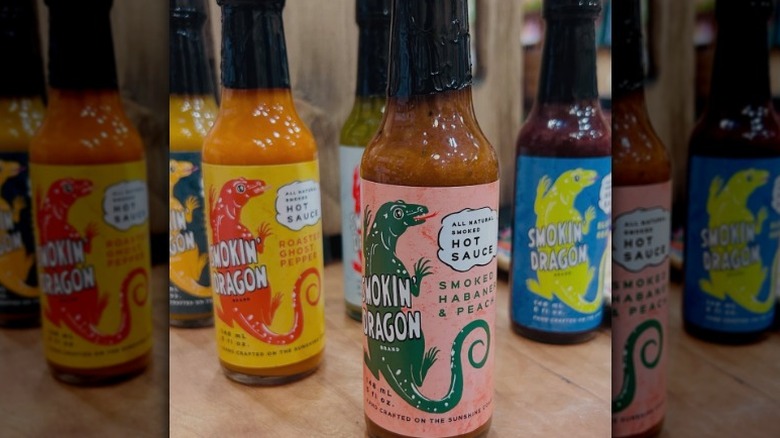 A bottle of Smokin' Dragon Smoked Habanero & Peach Hot Sauce in front of other Smokin' Dragon sauces.