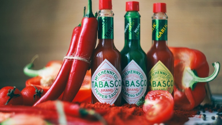 Several kinds of Tabasco sauce, with accompanying peppers.