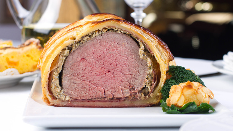 Beef Wellington sliced on a plate with vegetables