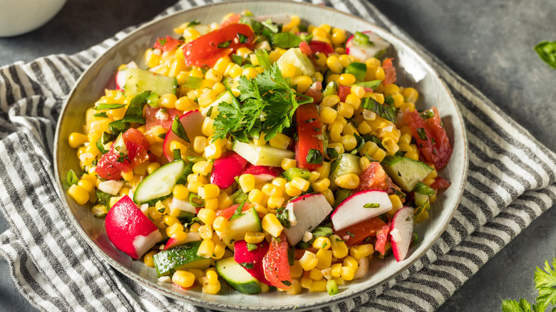 Bowl of corn salad with cucumbers and radishes