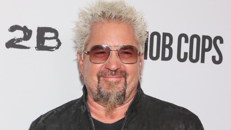 Guy Fieri smiling while wearing sunglasses at a movie premier.