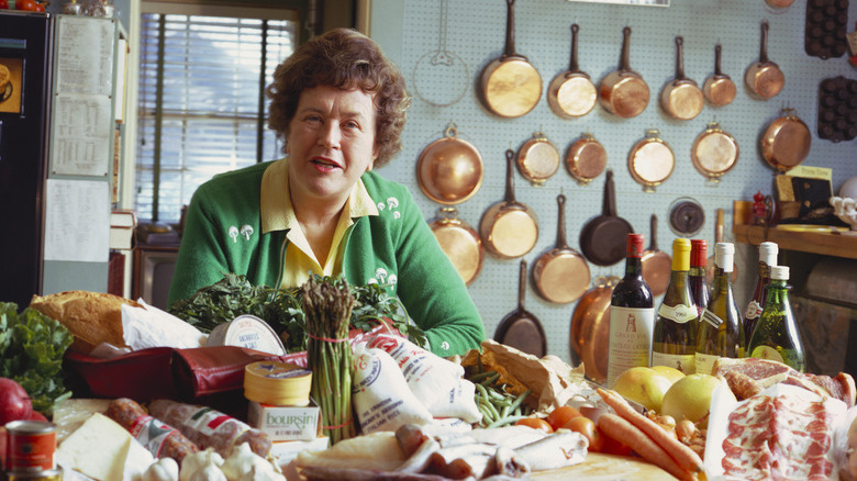 Julia child posing in a kitchen with food