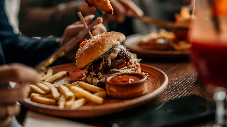 A gourmet burger on a plate with fries and ketchup