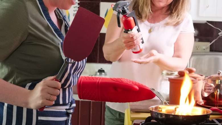 people using a fire extinguisher to put out kitchen fire