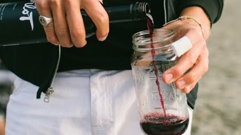 hands pouring wine into mason jar