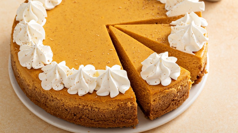 Pumpkin cheesecake with whipped cream with two slices cut