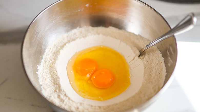 Eggs and flour in a stainless steel mixing bowl