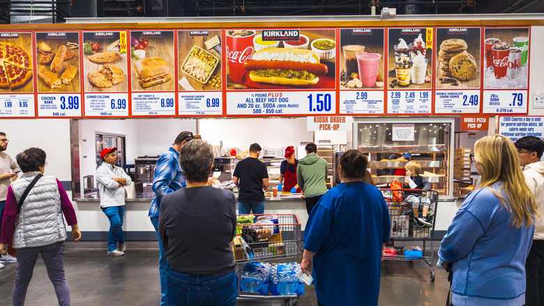 People waiting in line at the Costco food court for their orders.