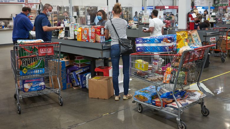 Costco customers with full shopping carts in the checkout line