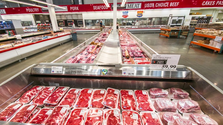 Costco meat department with open-faced refrigerators storing piles of meat products.