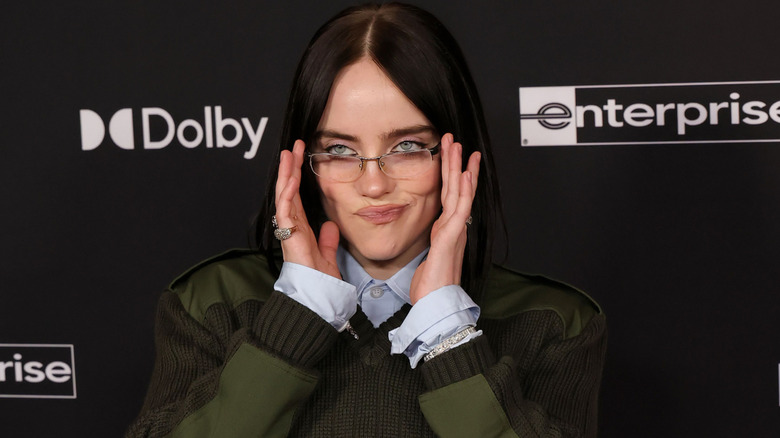 Billie Eilish humorously fiddling with her glasses on the red carpet