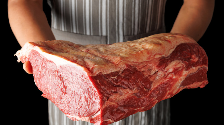 A butcher holds a primal cut of loin from which you could cut sirloin steaks