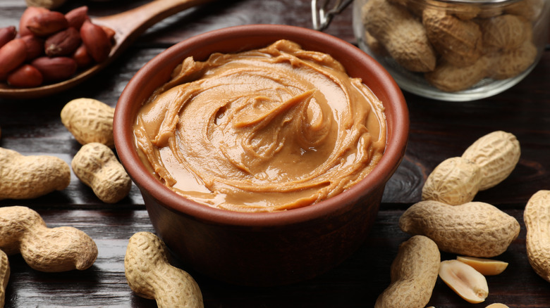 A small bowl of creamy peanut butter with peanuts in shells