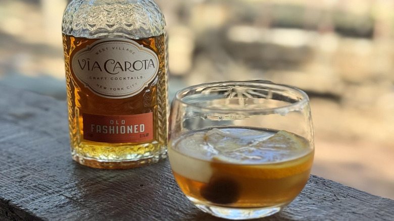 Via Carota ready-to-pour Old Fashioned cocktail next to a rocks glass.