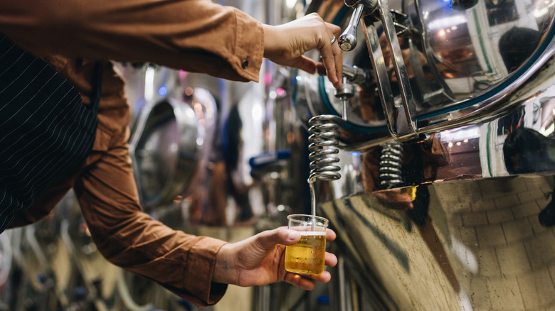 Woman pouring beer in brewery